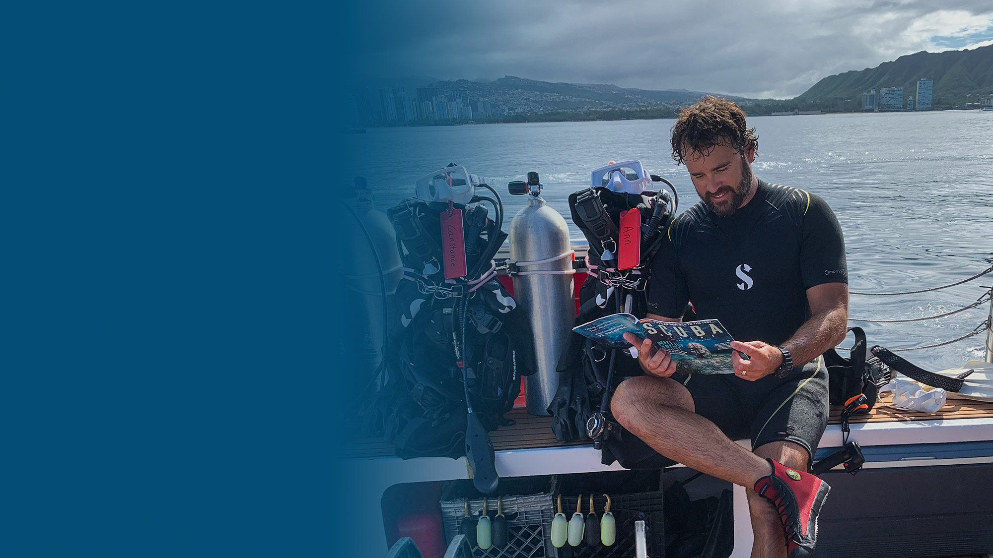 sdm-club4.2-2000x1125.jpg scuba diver reading scuba diving magazine on a boat