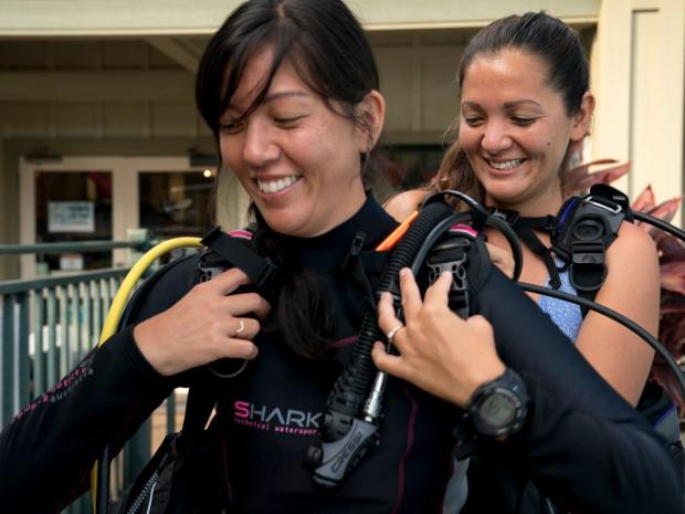 Person helping a diver get ready.