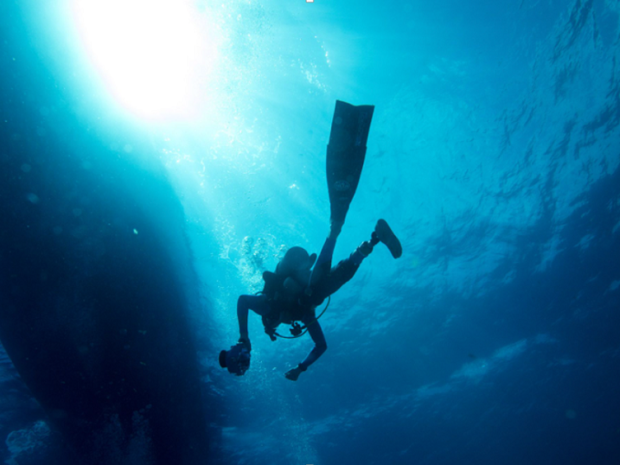 Scuba diver diving beneath a boat