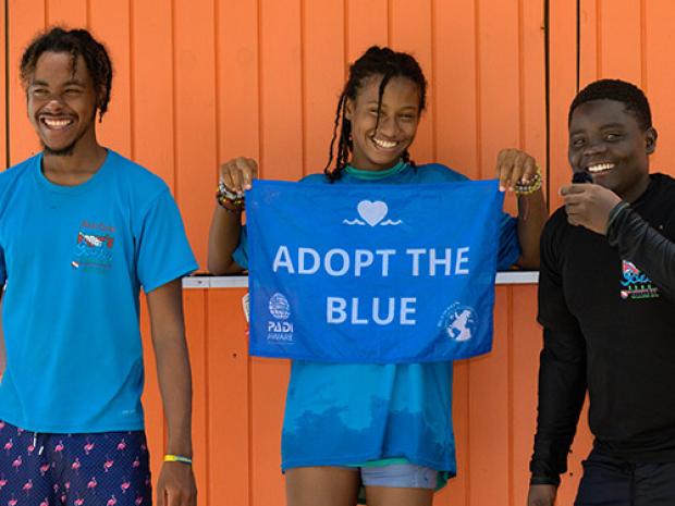 A group of people holding up an Adopt the Blue towel.