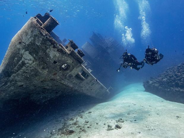 scuba divers diving next to a wreck