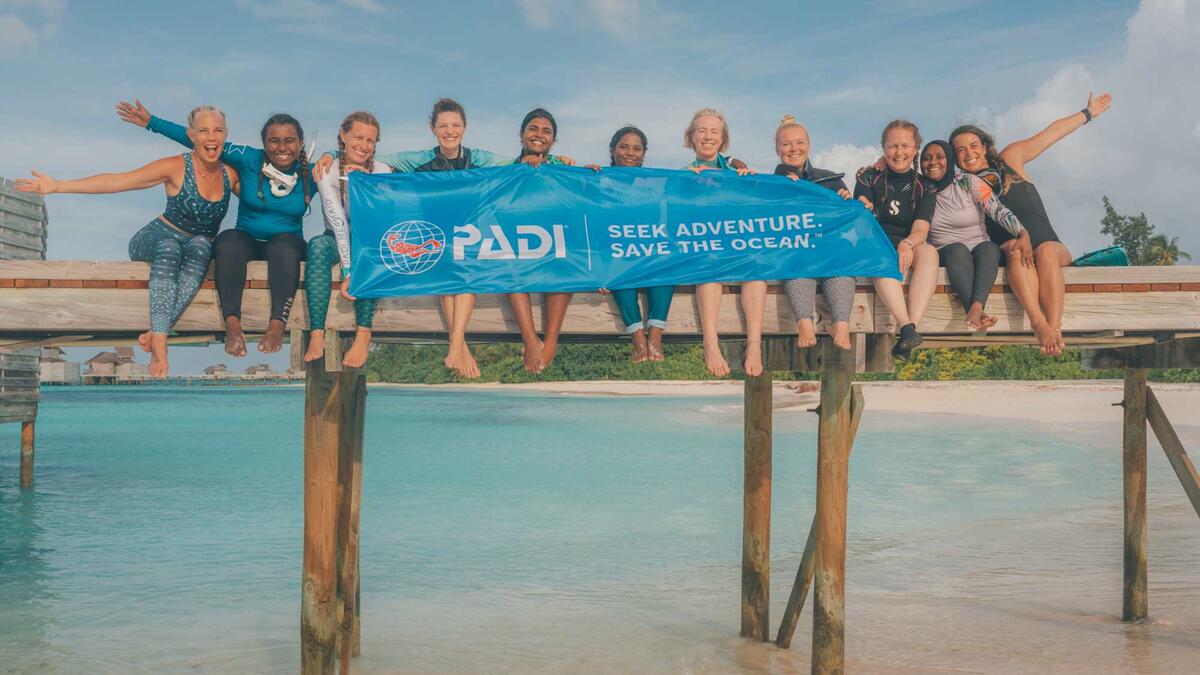 a group of women divers holding padi banner